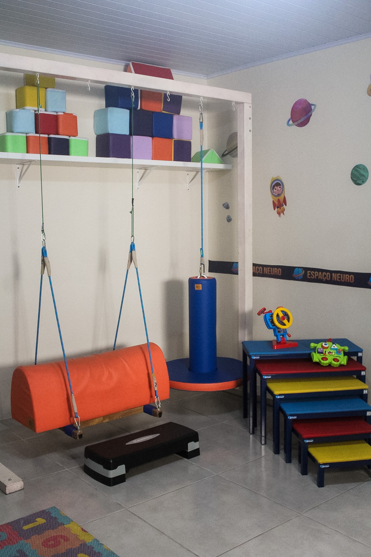 Sala com balanços, degraus e aparelhos de fisioterapia infantil